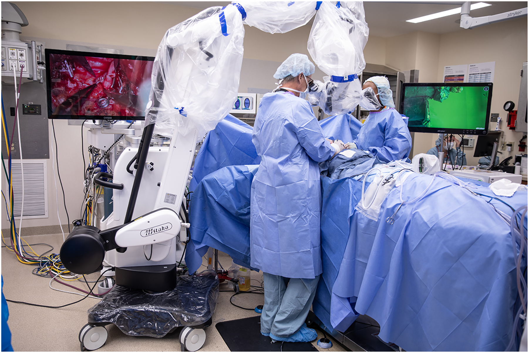 A photo shows a team of surgeons operating with a robotic-assisted surgical system and monitors showing magnified views of the procedure.